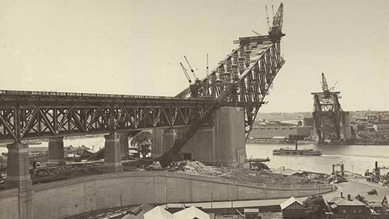 black and white photo of the early construction of the sydney harbour bridge